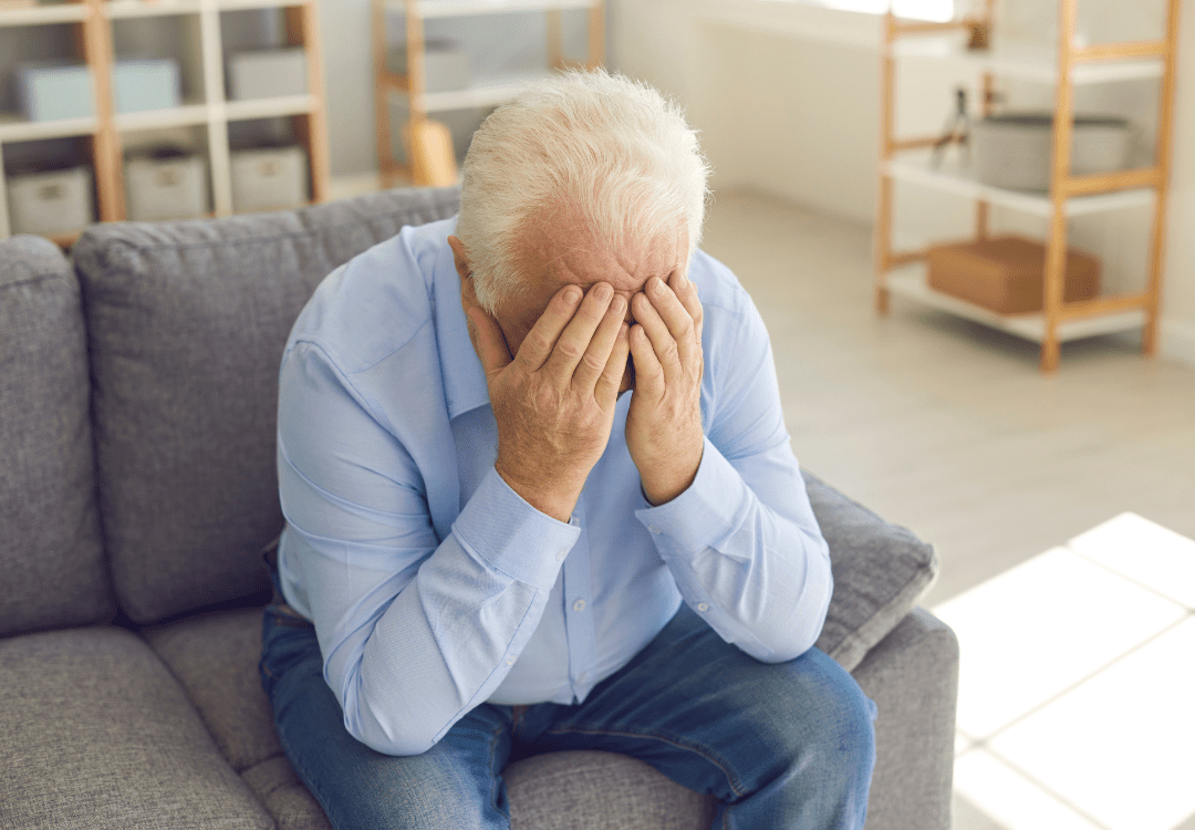 old man with his hands on his face suffering from hearing exhaustion