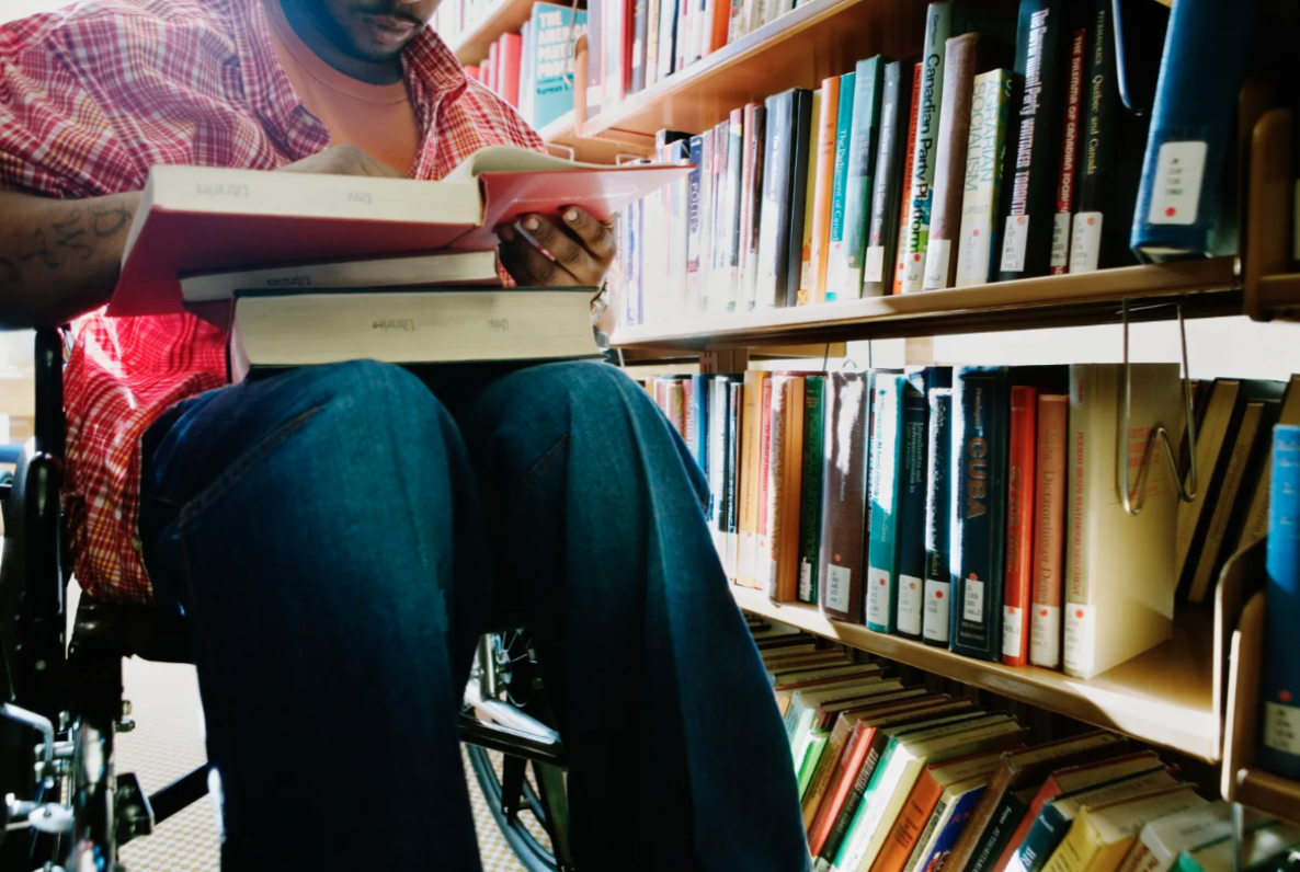 A man in a wheelchair looking at books in a library.