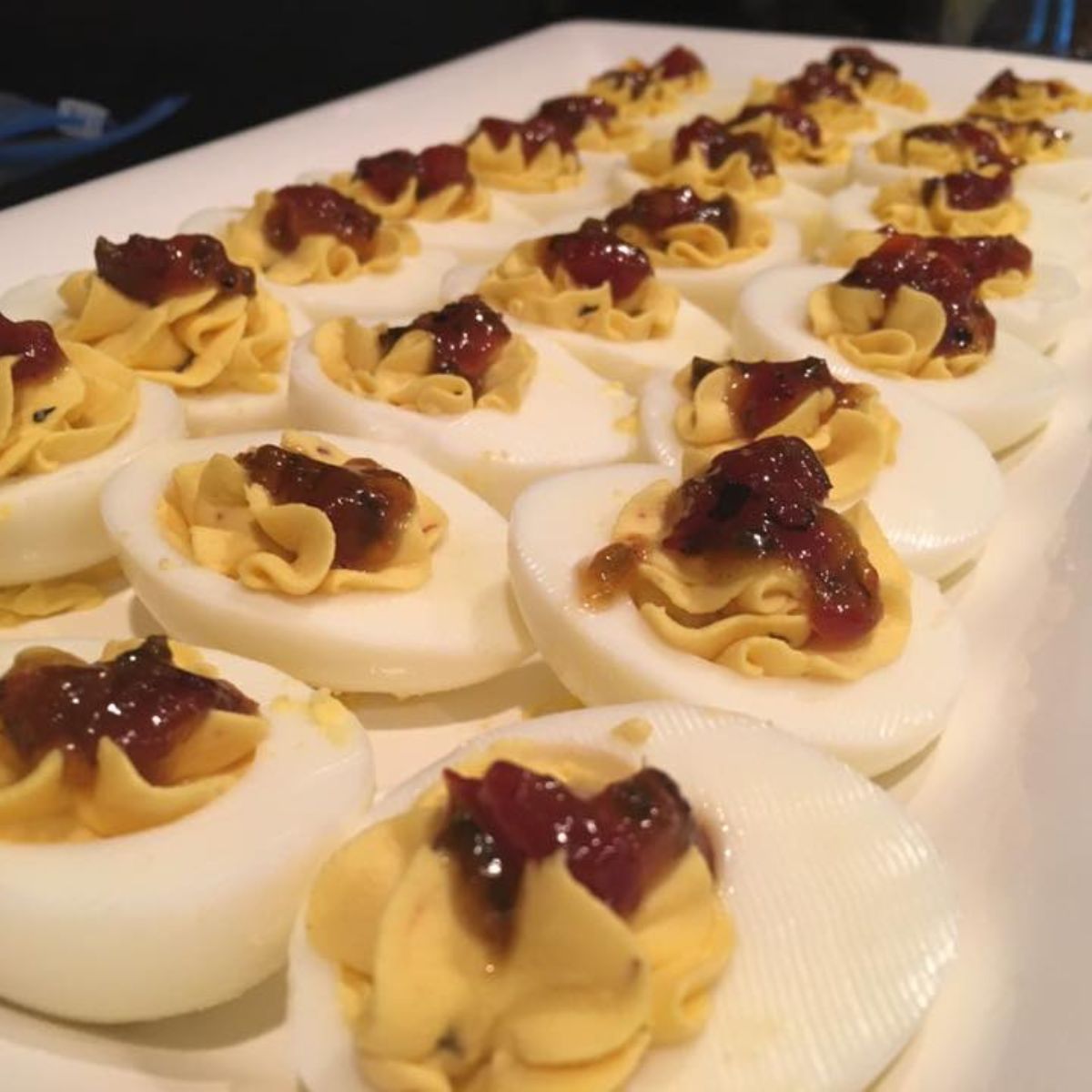 Platter of deviled eggs topped with bacon jam.