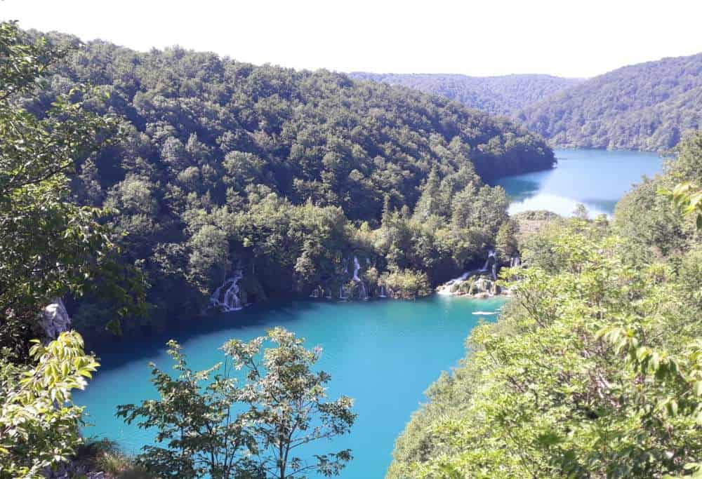 View from the top of the mountain in Plitvice National Park, Croatia. Blue lake surrounded by green trees.
