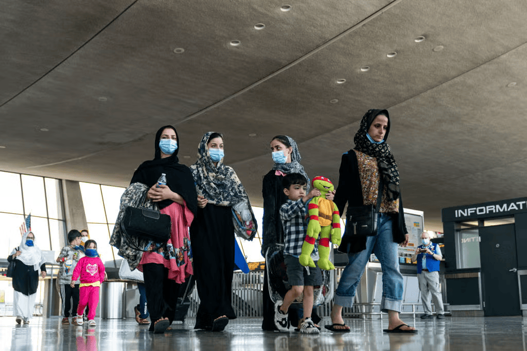 Afghan families walk to a bus that will take them to a refugee processing center at Dulles International Airport on August 24, 2021 in Dulles, Virginia. According to the U.S. State Department, between Sunday morning and Monday morning, 10,400 people were evacuated from Kabul on military flights and approximately 5,900 more people were evacuated on 61 coalition aircraft.(Photo by Joshua Roberts/Getty Images)