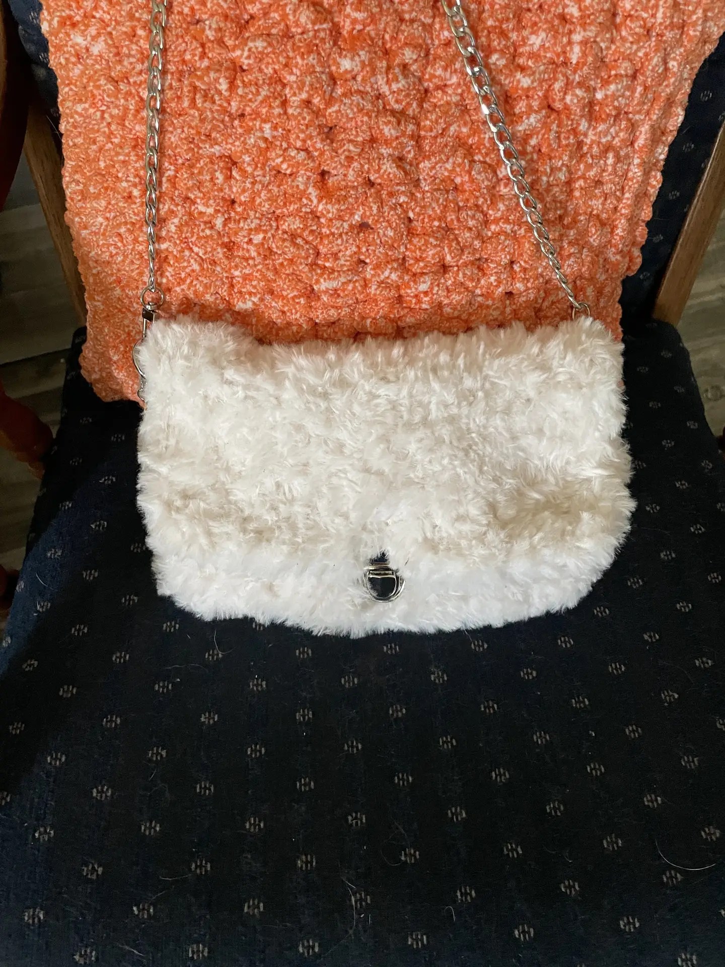 Soft faux fur shoulder bag in creamy white, featuring a silver chain strap, zippered interior organizer, and a small pink smiley face charm hanging from the strap.