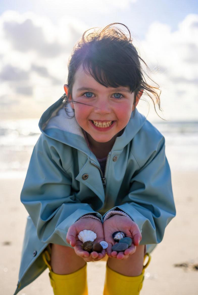 Smiling confident child holding seashells on the beach representing child self-esteem and confidence development