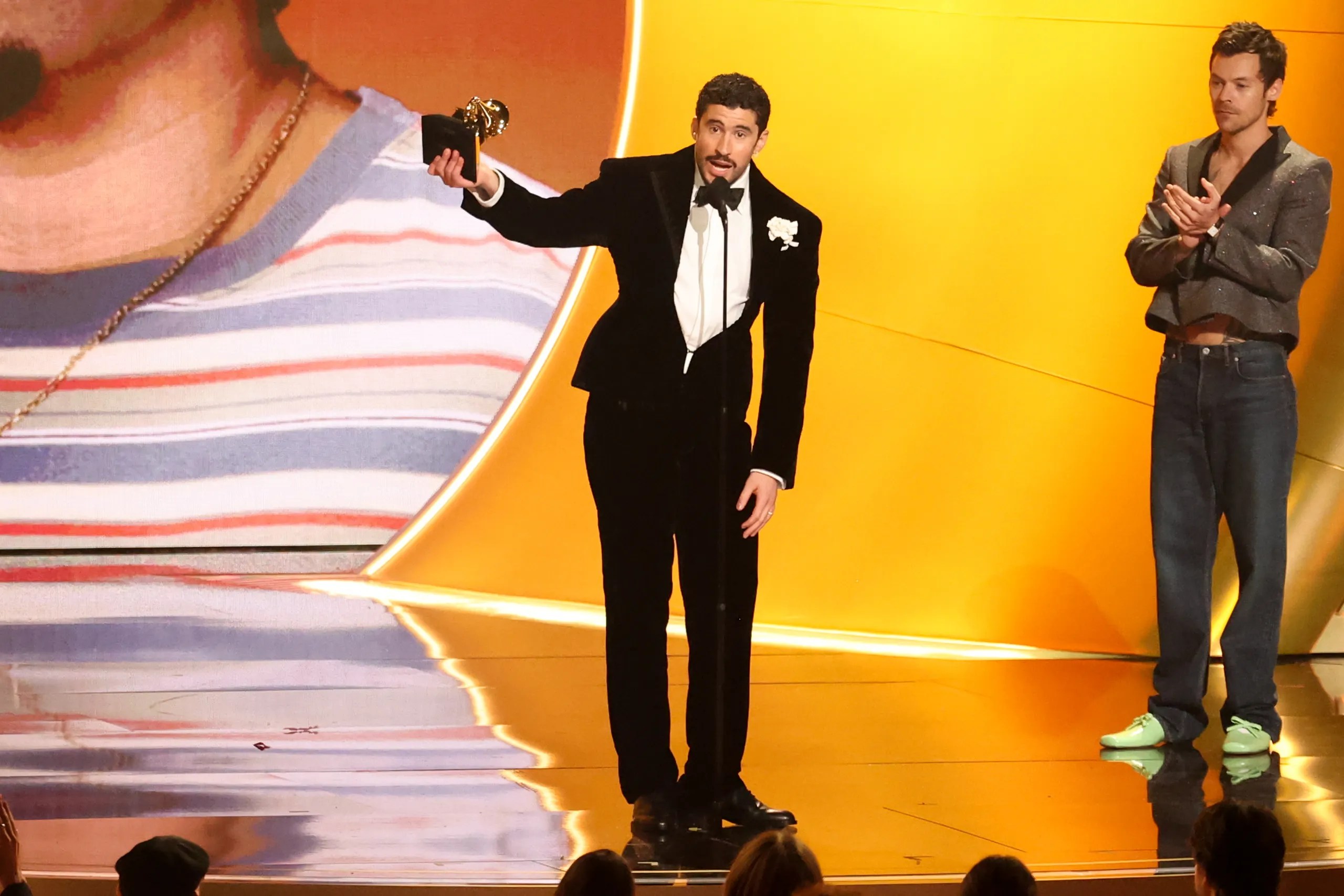 Musician Bad Bunny holds up a Grammy Award as he speaks into a microphone at the 2026 Grammy Awards.