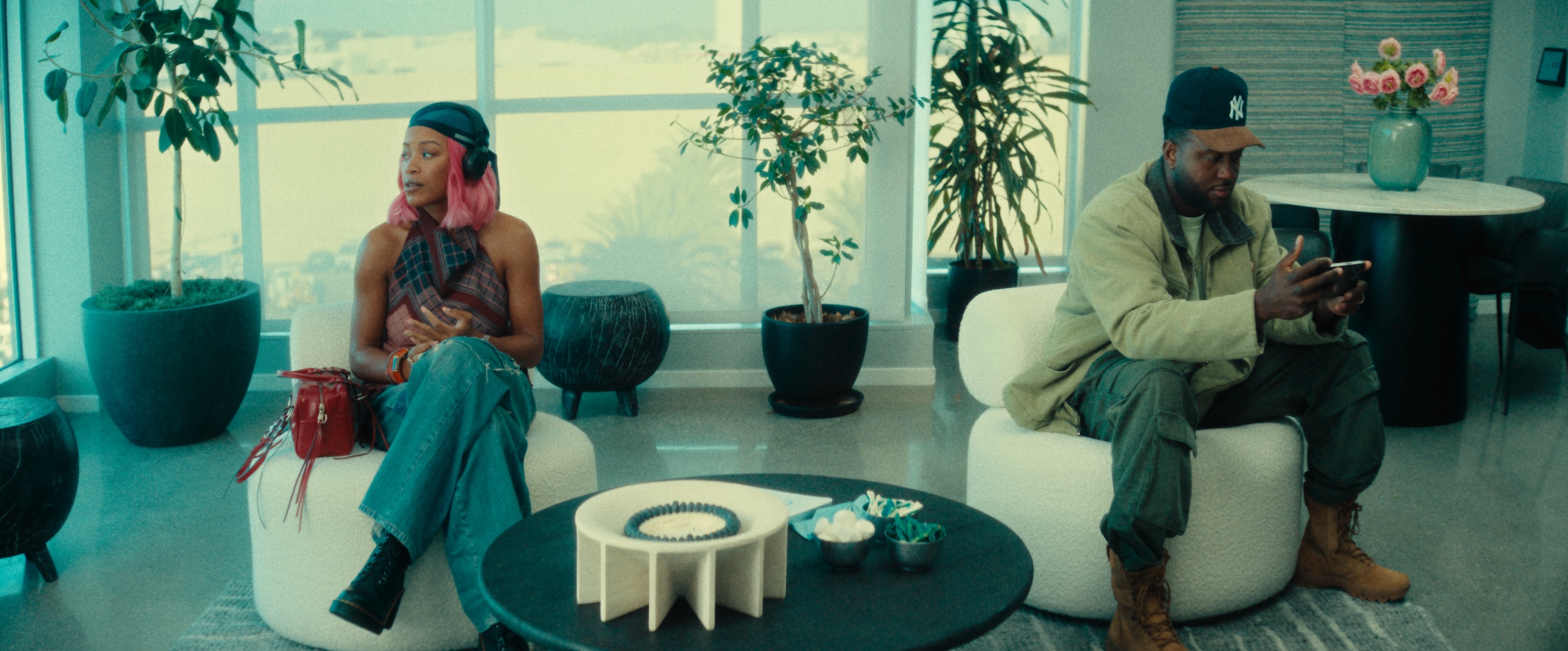 Actors Chanté Adams and Sinqua Walls sitting near each other in a lobby.