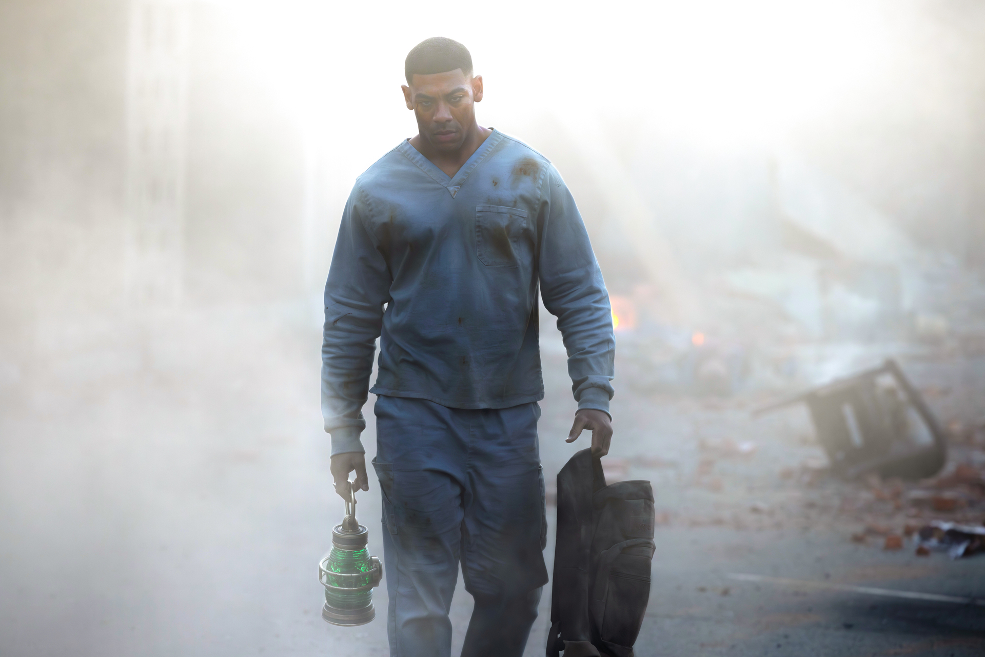 Aaron Pierre as John Stewart, wearing a blue jacket and carrying a bag, walking alone at dusk in a promotional image for HBO's "Lanterns."