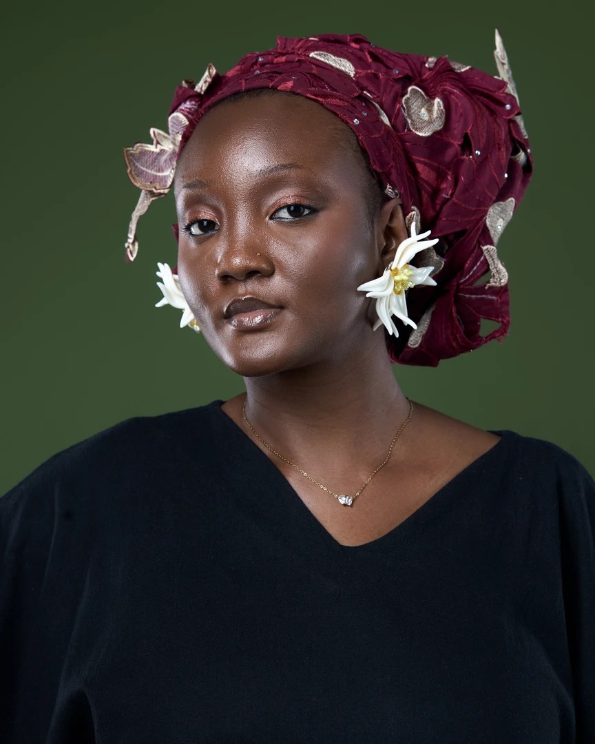 Faith Martins, Nigerian artiste behind the Afro-House single “DÀJÚ,” photographed in a black outfit and red lace gele. The singer has incorporated gele and other elements of Nigerian visual culture into the imagery surrounding her emerging music career.