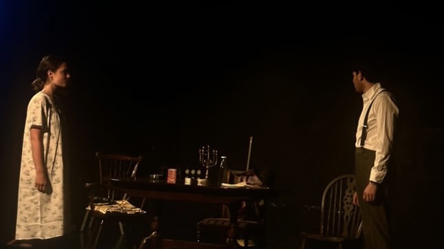 Two people standing next to a table on a dimly lit stage