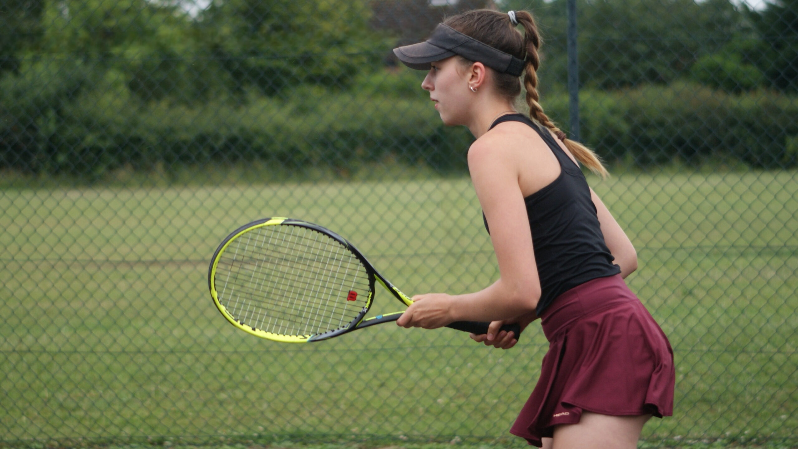 A girl playing tennis on an outdoor court.