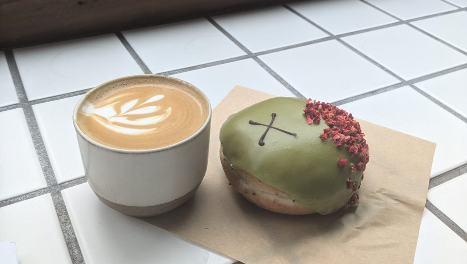 A coffee and an artsy doughnut sit on a countertop.