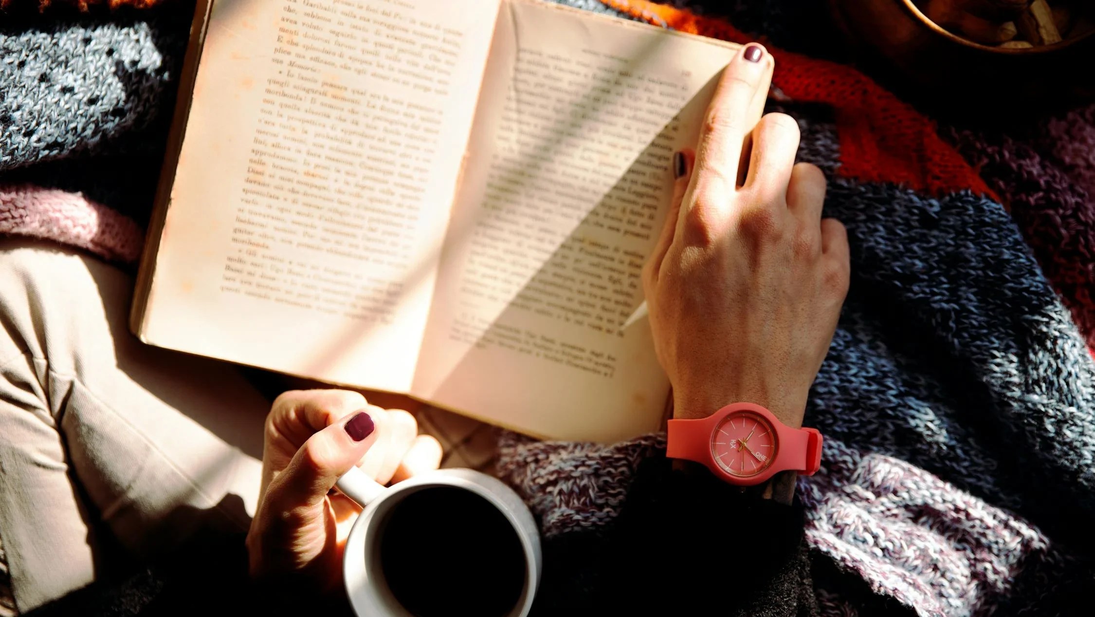 Person Reading Book and Holding Coffee