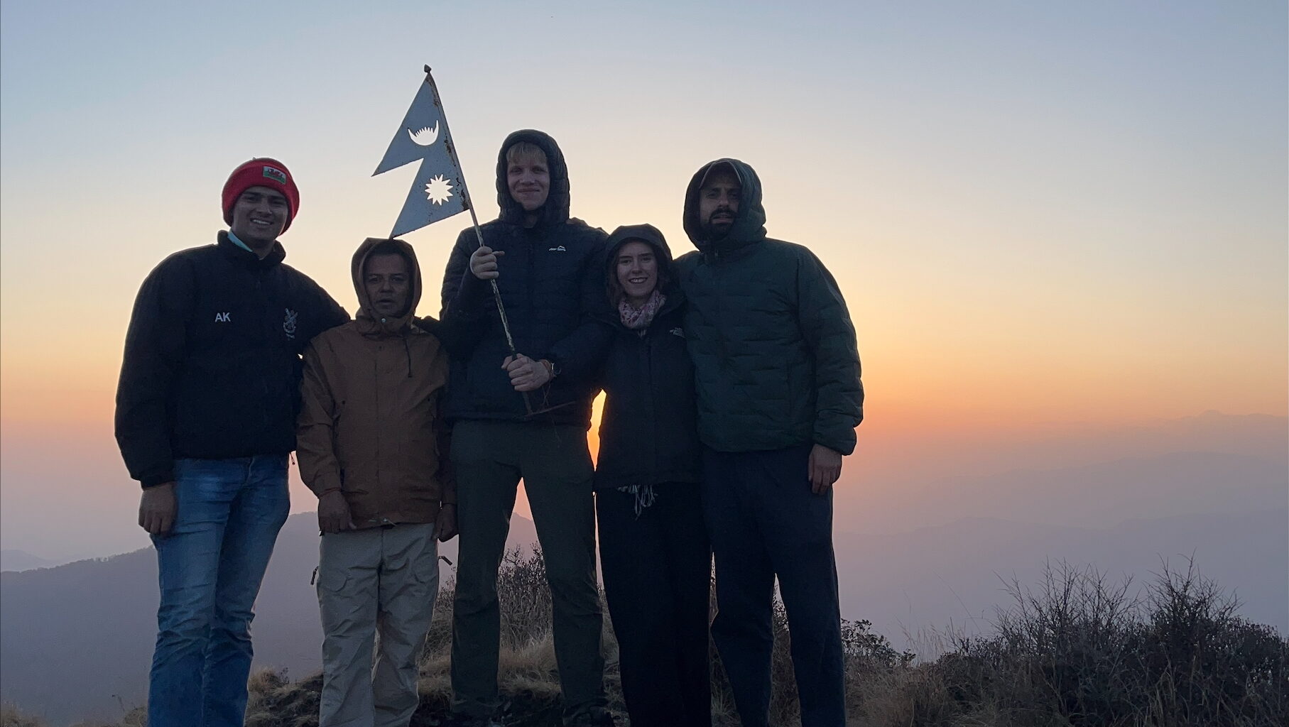 4 people stood on a mountain in Nepal at sunrise