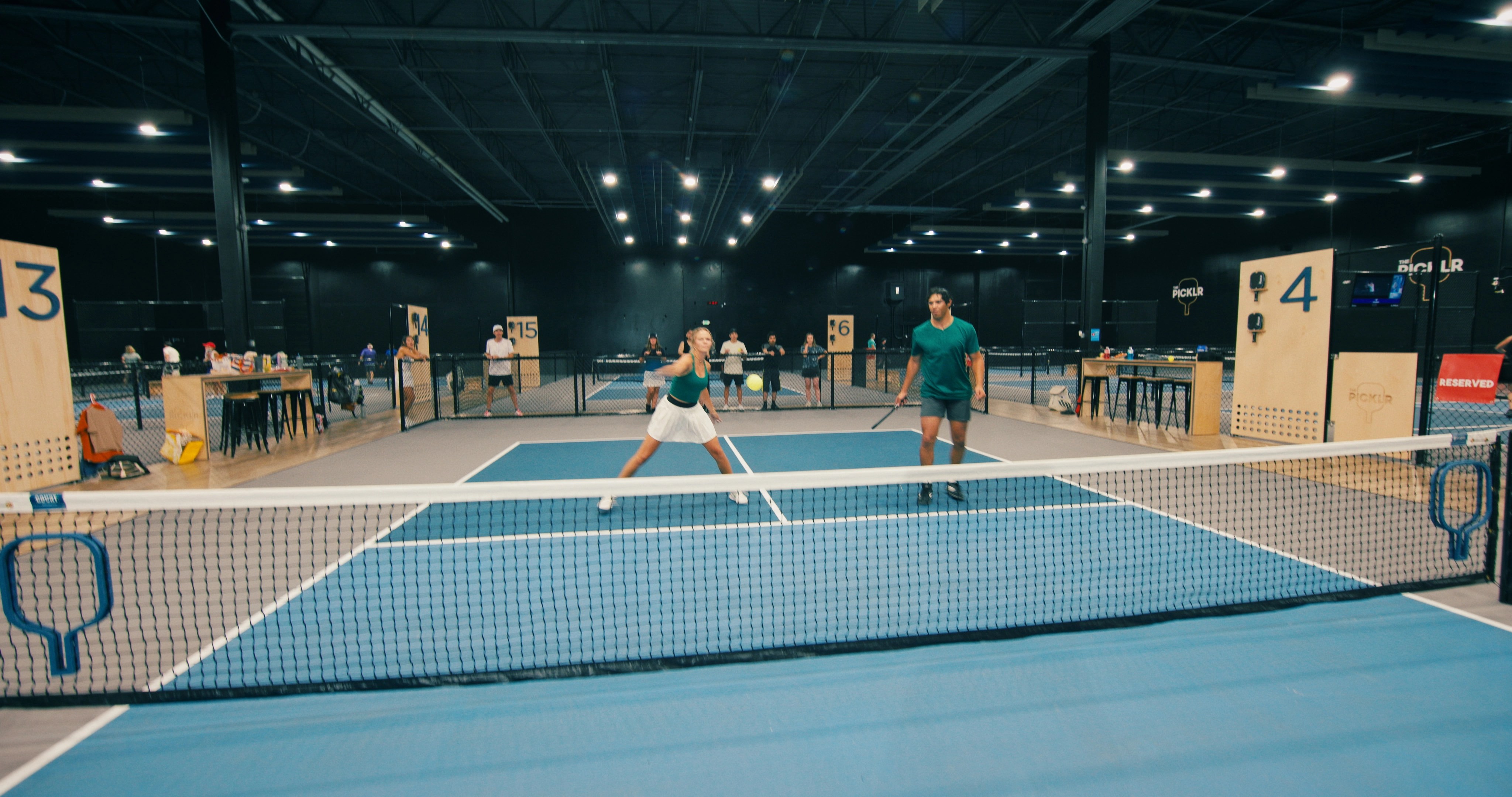 Female pickleball mid-swing in doubles match