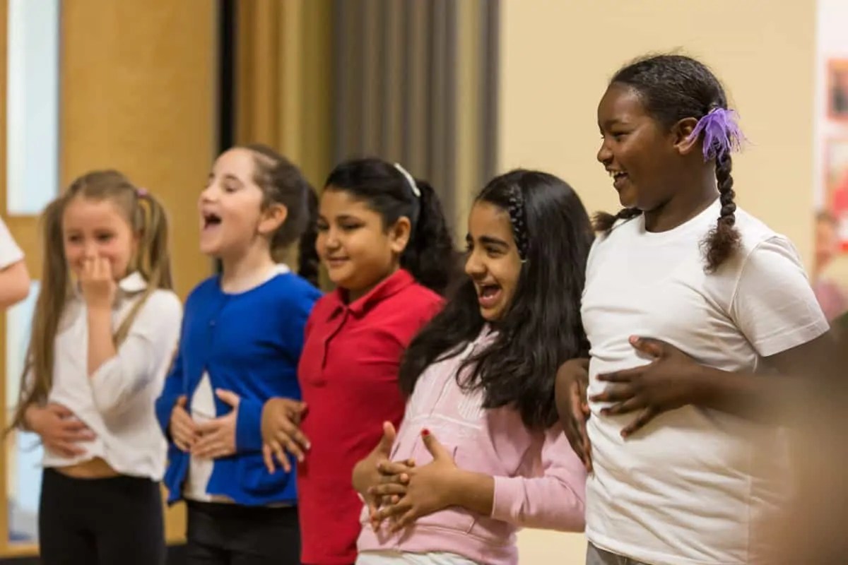 a group of children hold their stomachs and laugh as part of a drama and dance session by darts in Doncaster