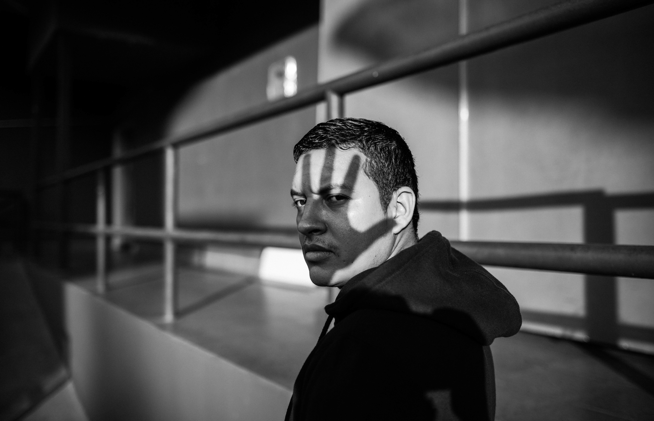 Black and white photograph of a man with the shadow of a hand over his face.