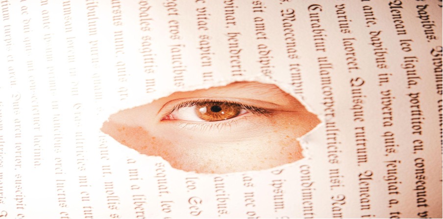 Cropped image of an eye set in the middle of a sideways page of text.