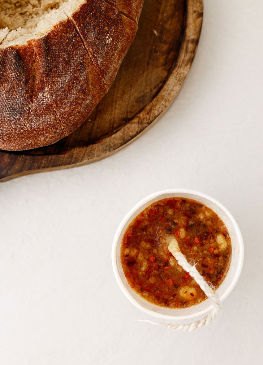 a hot honey butter candle cooling in a paper cup next to a loaf of sourdough bread