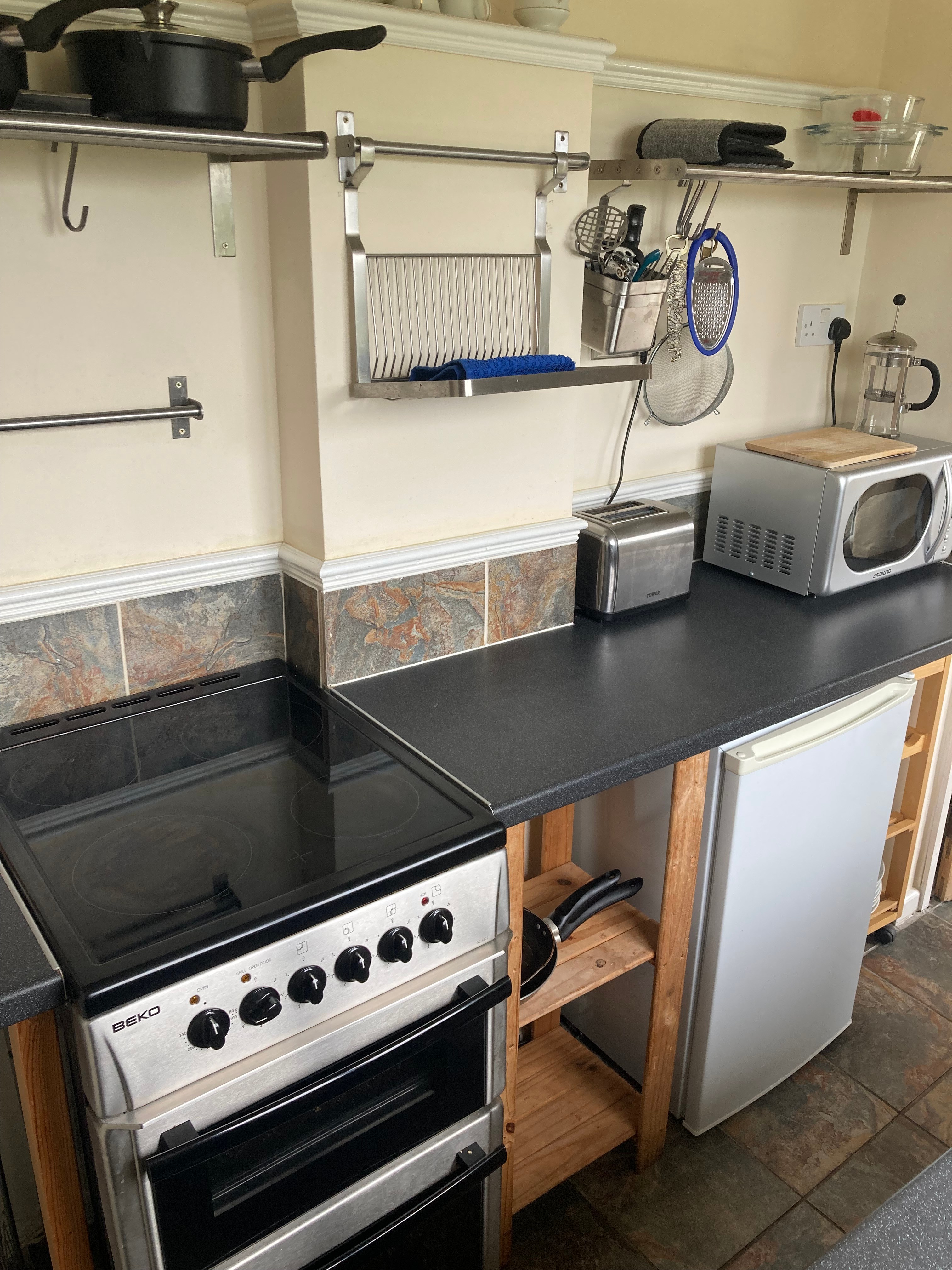 The kitchen has a cooker, microwave and fridge