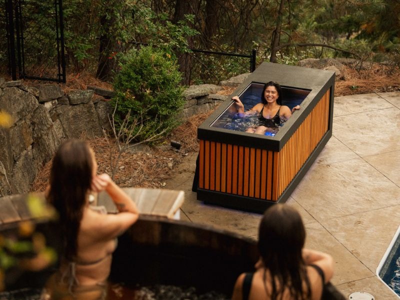 Woman using a modern outdoor cold plunge beside a landscaped forest setting in Vancouver
