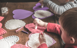 Children sitting at a table making Valentine heart crafts together, building connection through play and creativity.