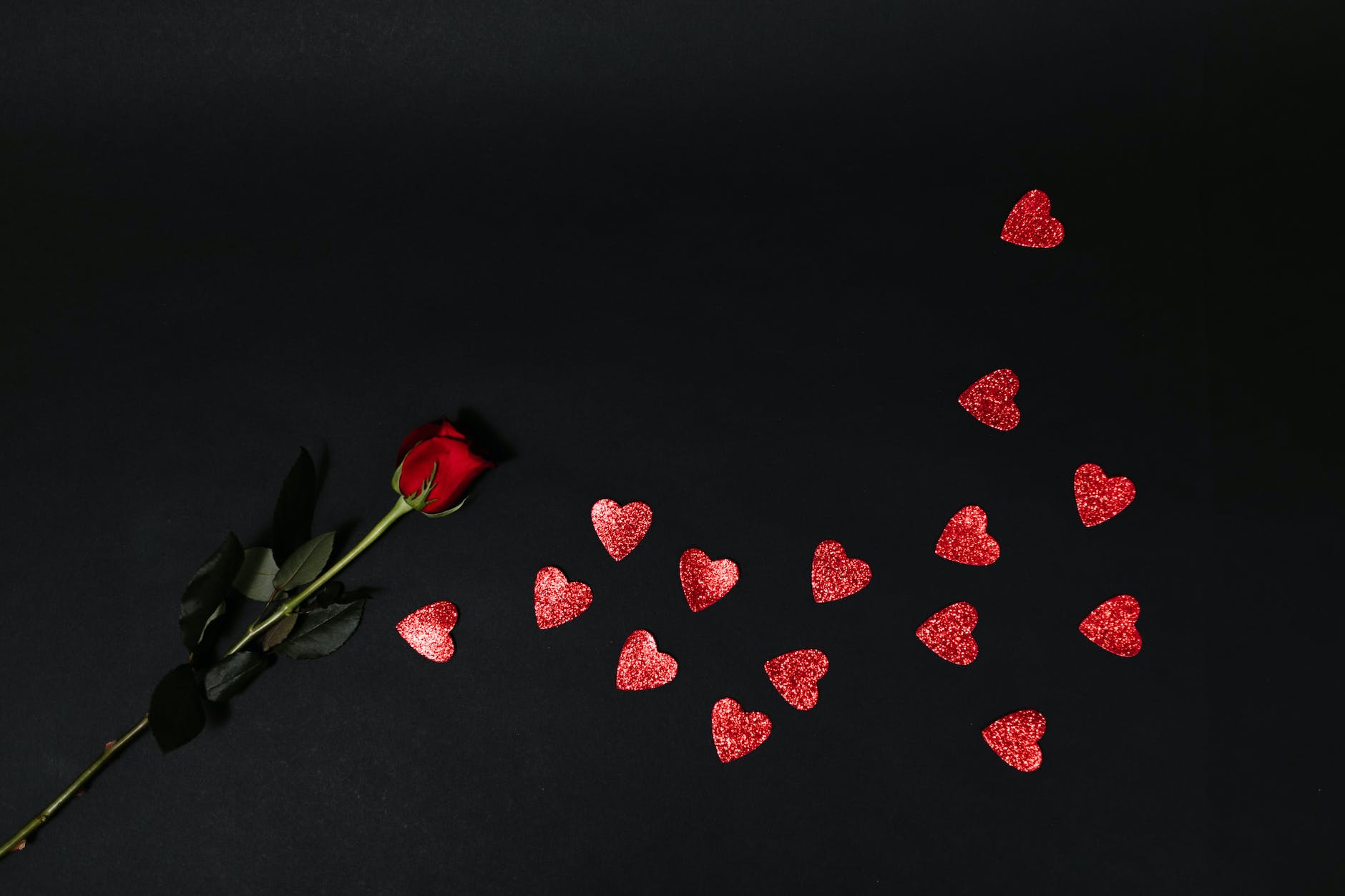 red rose and red heart shapes on black surface
