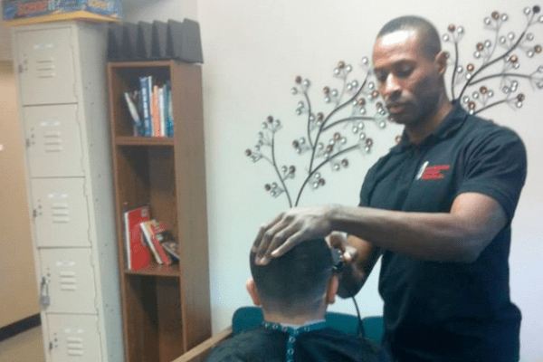 a man cutting a boy's hair in a barber shop.