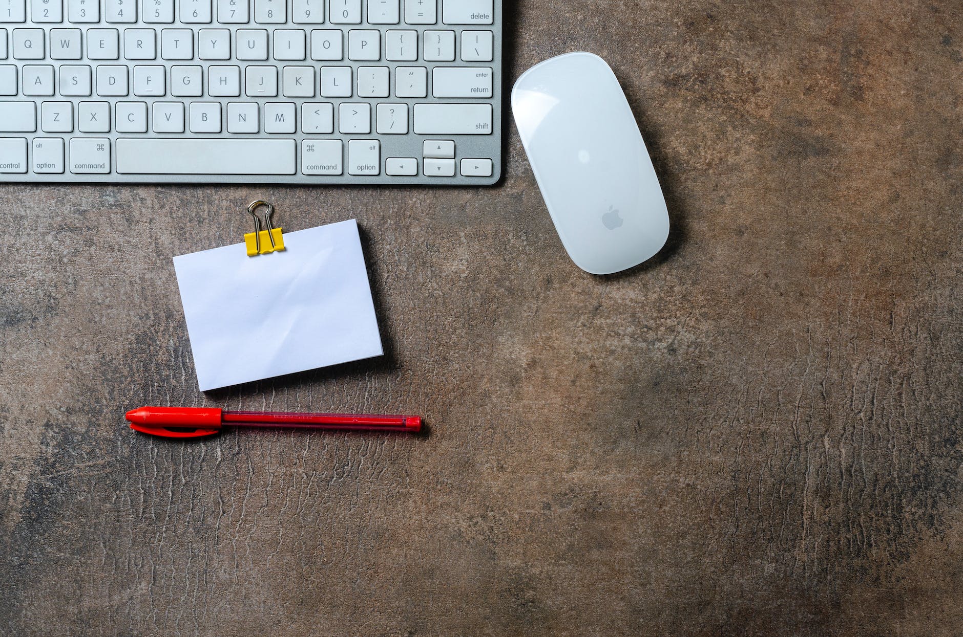 red pen and sticky note by keyboard and mouse on desk