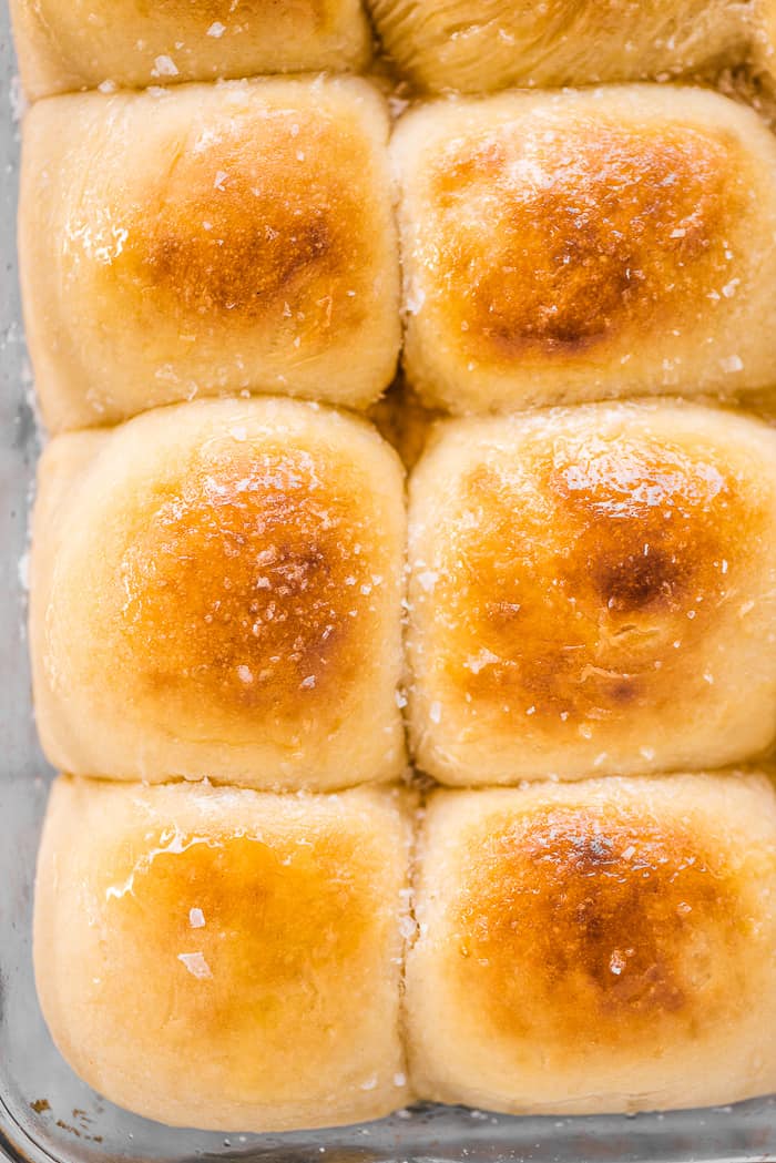These potato rolls are light, fluffy, and absolutely delicious. They make the perfect dinner buns and are great for sandwiches and dipping into soup, too. Potato buns in a baking pan with honey butter on top.