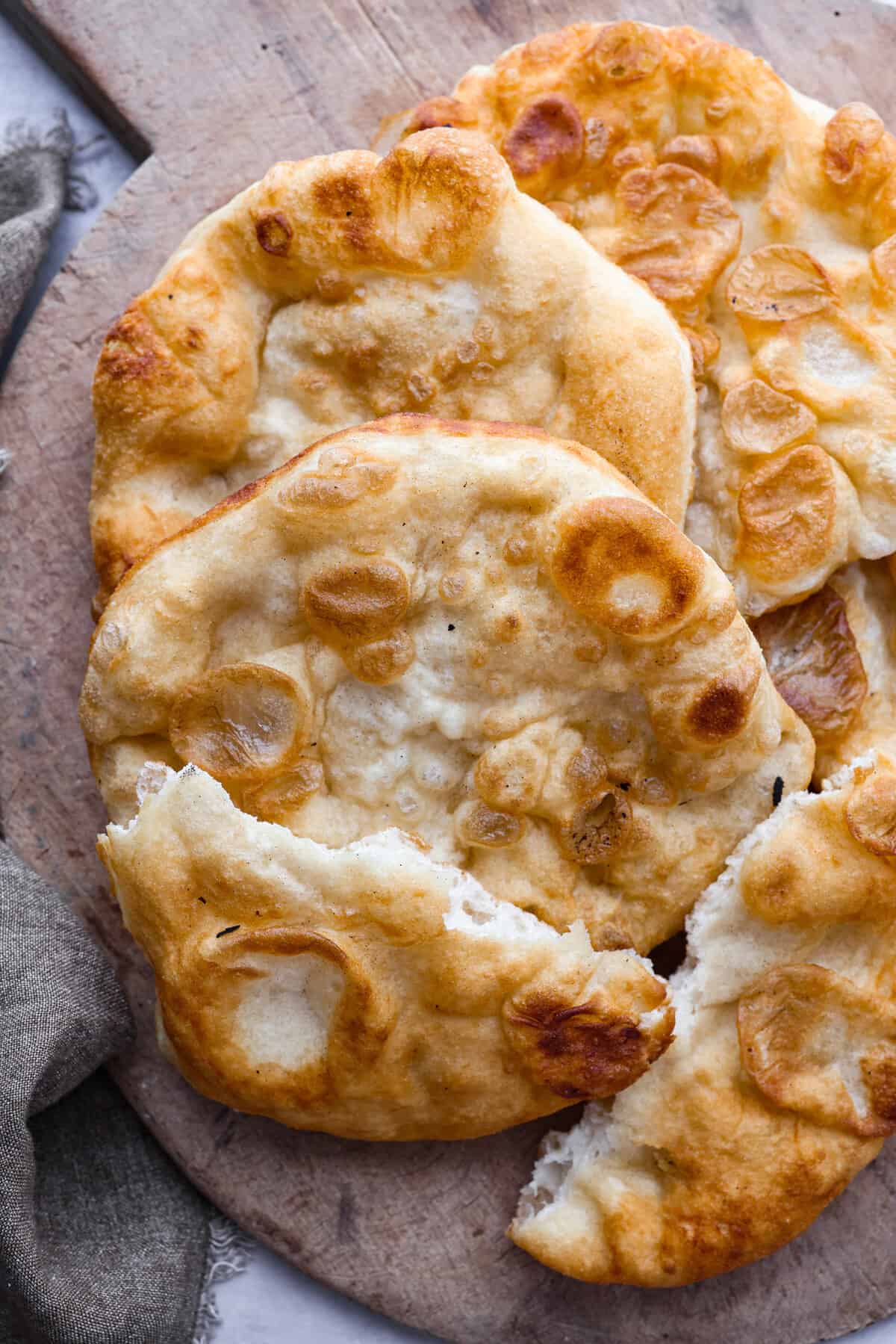 The perfect combination of airy, soft, and chewy, you NEED this homemade fry bread in your life! It's so versatile. You can enjoy it as-is, or use it as a canvas for all kinds of tasty sweet and savory creations. Top-down view of fry bread with one piece torn in half.