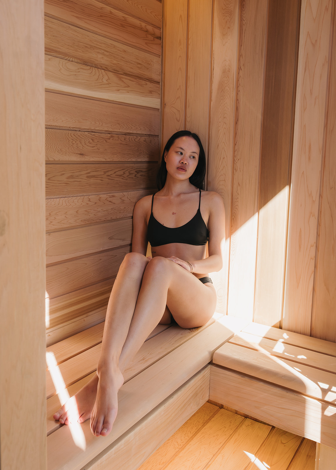 young asian woman sitting solo in an outdoor sauna