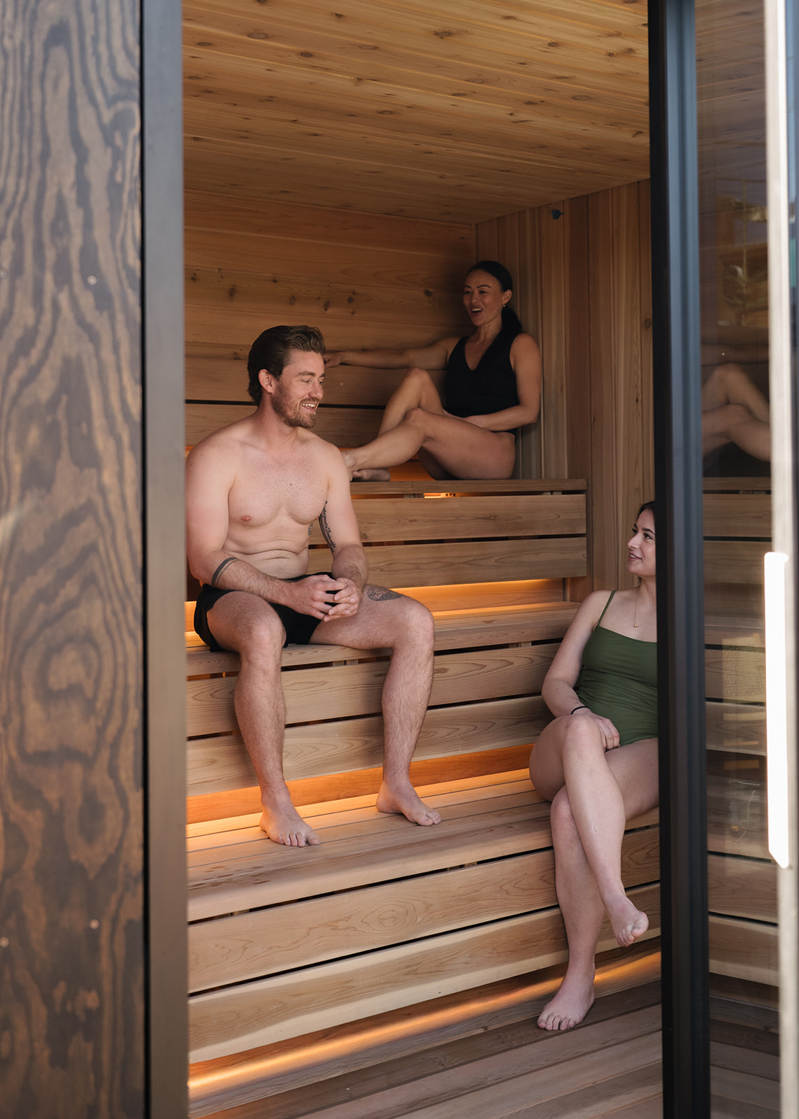 group of men and women sitting and resting in an outdoor sauna