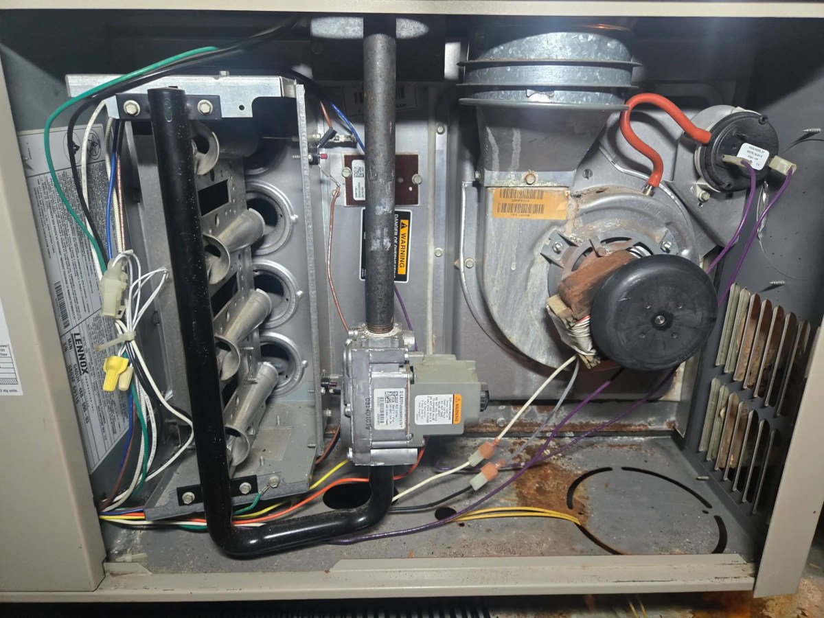 Gas furnace opened during a professional real estate HVAC inspection showing internal heating components.