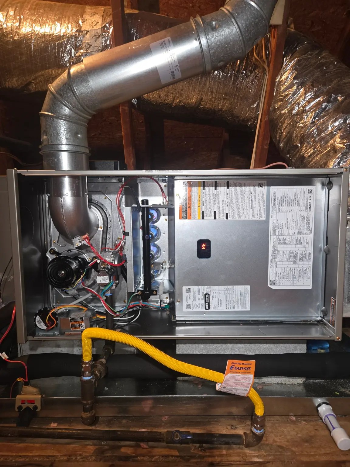 New Bryant gas furnace installation with the service panel removed, showing the burner compartment during a residential HVAC system replacement.
