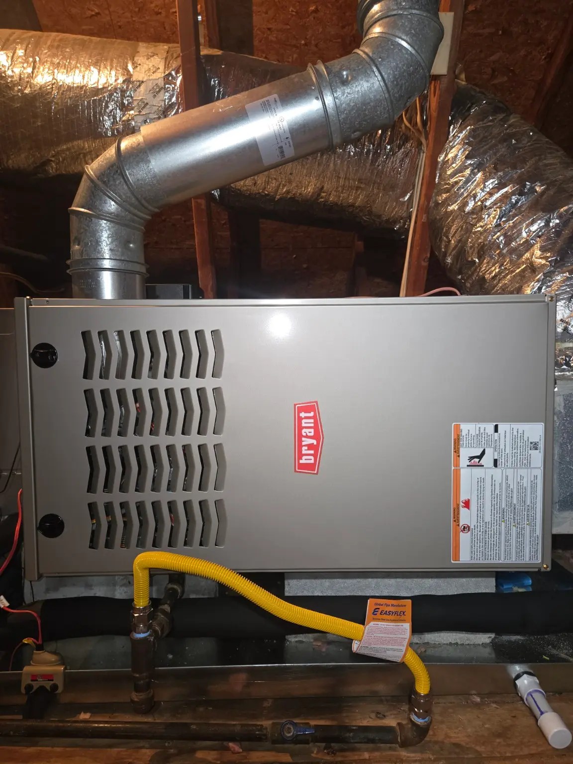 New Bryant gas furnace installed in a residential attic after professional heating system replacement with the cabinet fully assembled.