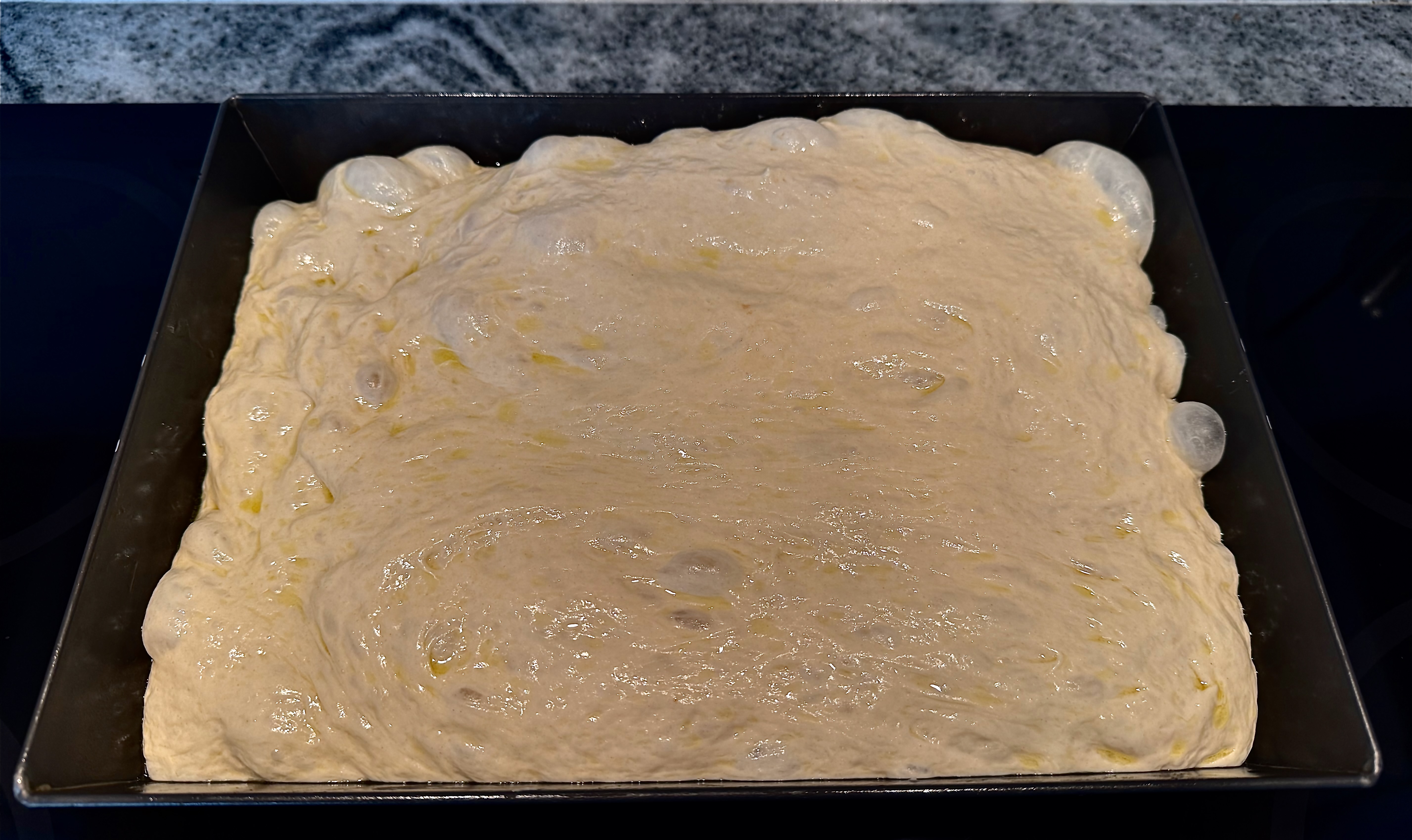 Focaccia dough resting in the pan before baking