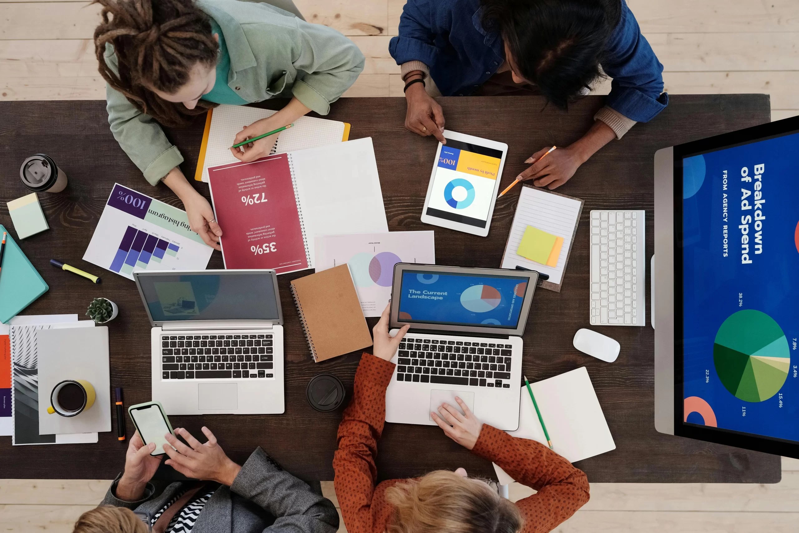 Overhead view of a team working with laptops and printed charts