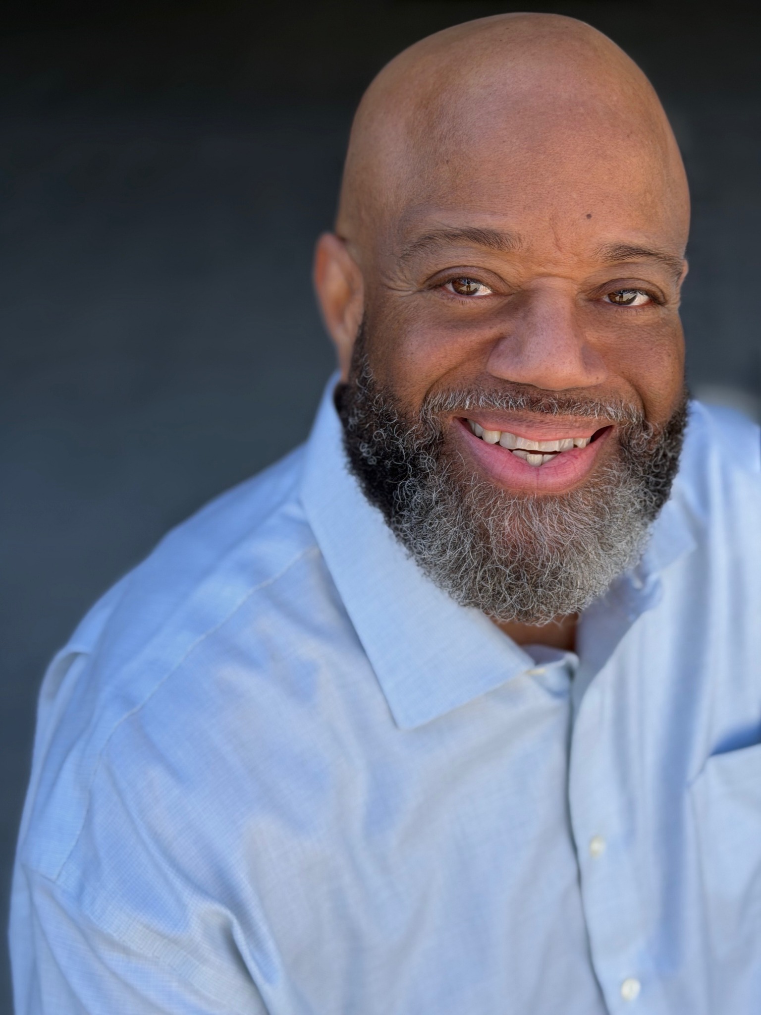 Mark Christopher Lawrence smiling in a light blue shirt