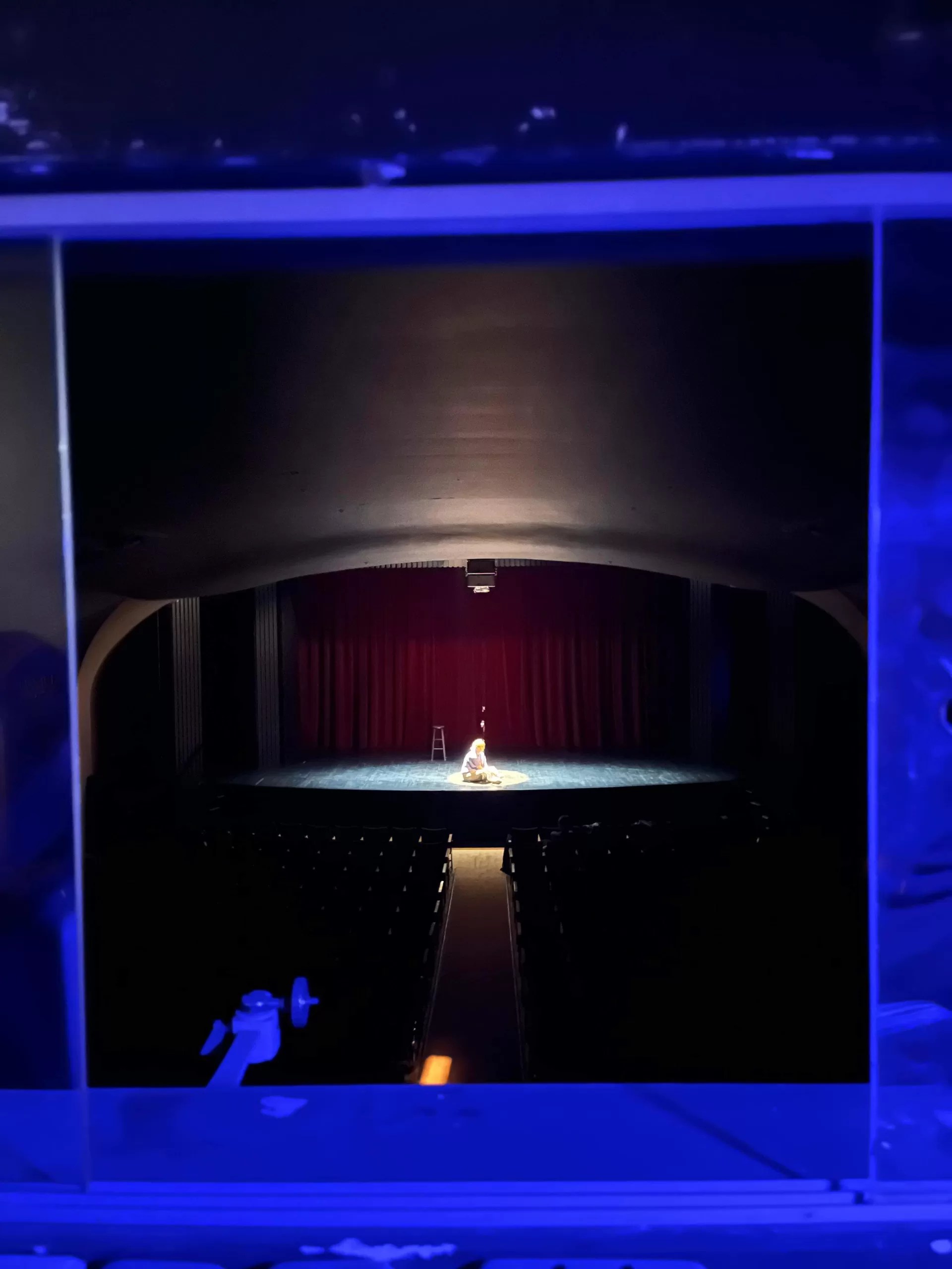 Brynn Bonne, the star of Jackes and Jills, sits isolated in a spotlight on the stage of Hart House Theatre