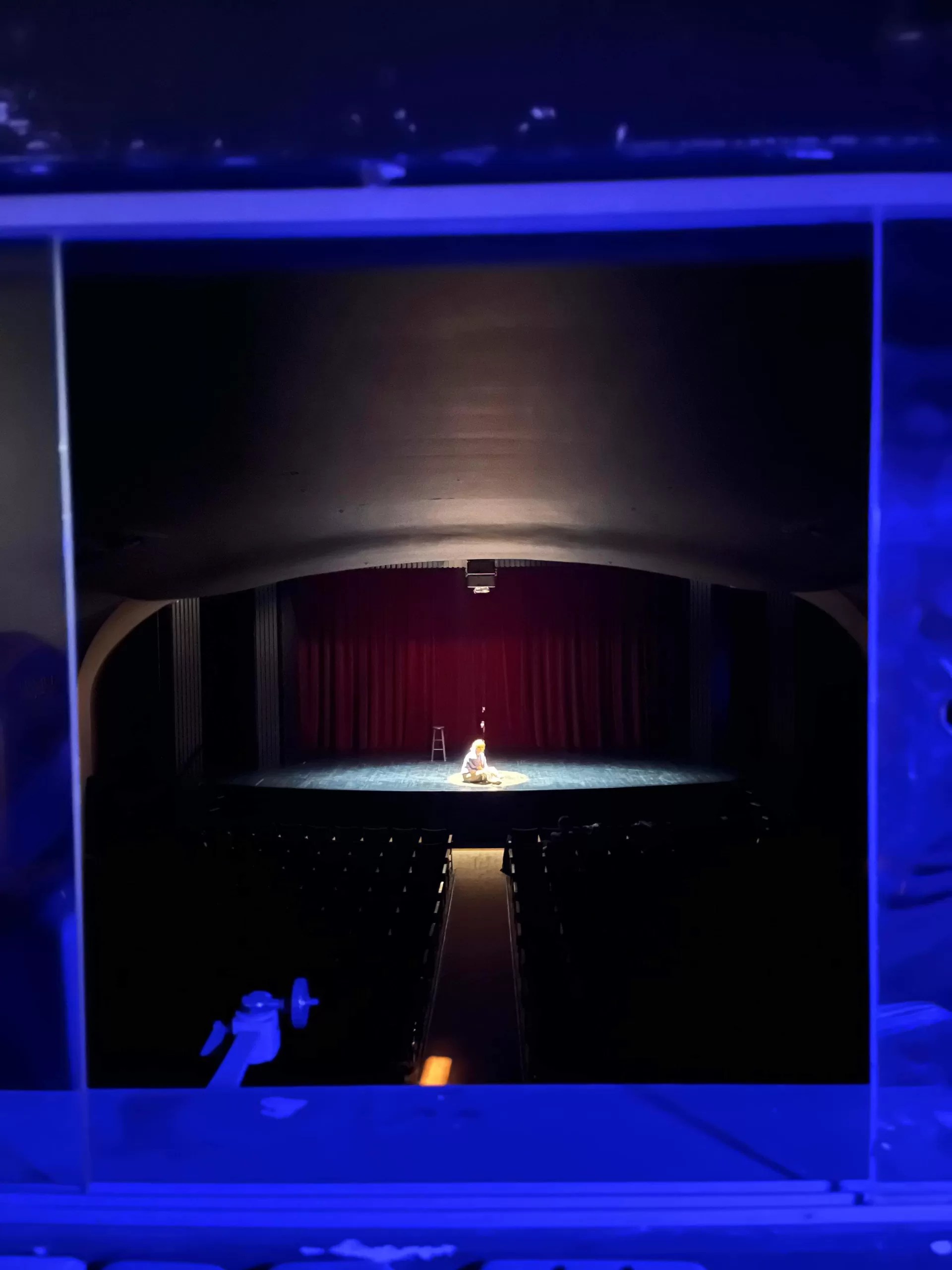 Brynn Bonne, the star of Jackes and Jills, sits isolated in a spotlight on the stage of Hart House Theatre