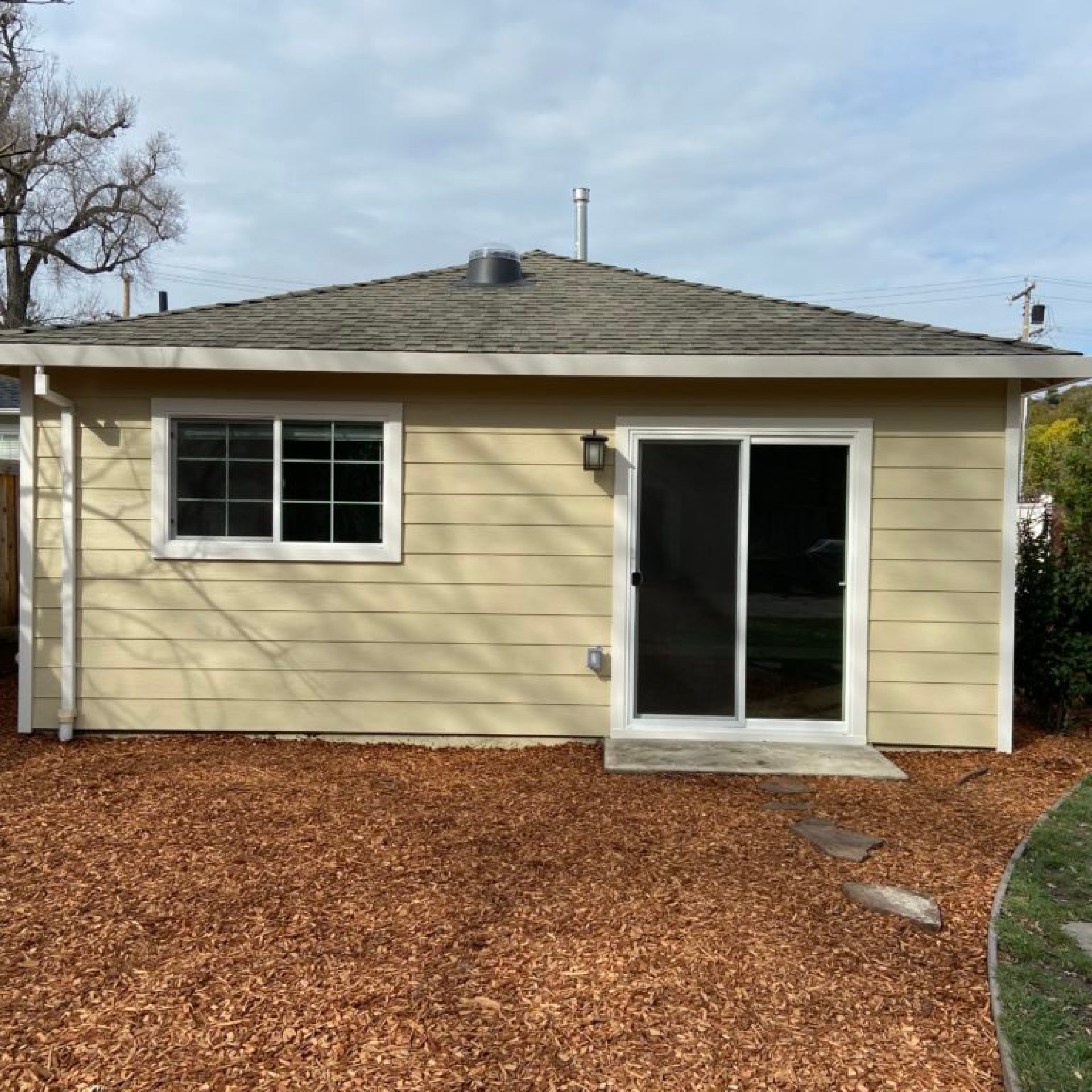 South ADU wall after renovation with siding and sliding glass door
