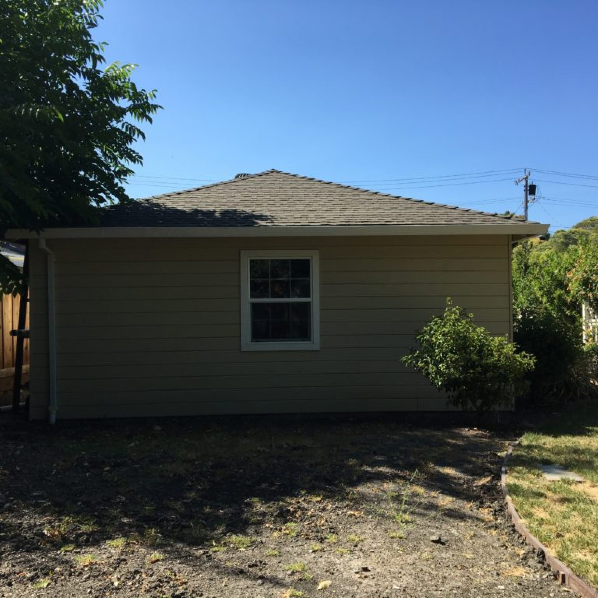 South garage wall before renovation with small window and dry yard