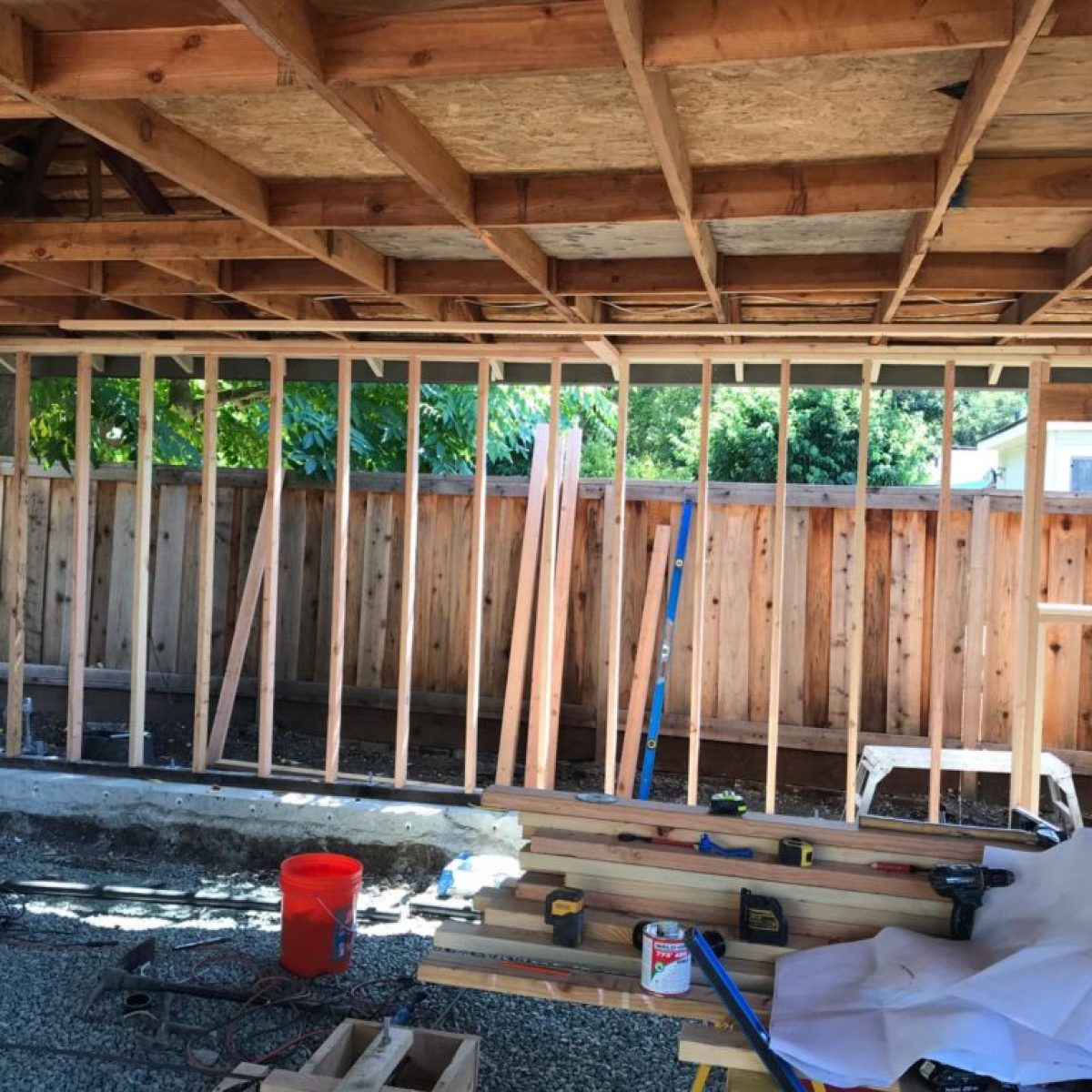 West wall wood framing under construction with lumber and ladder