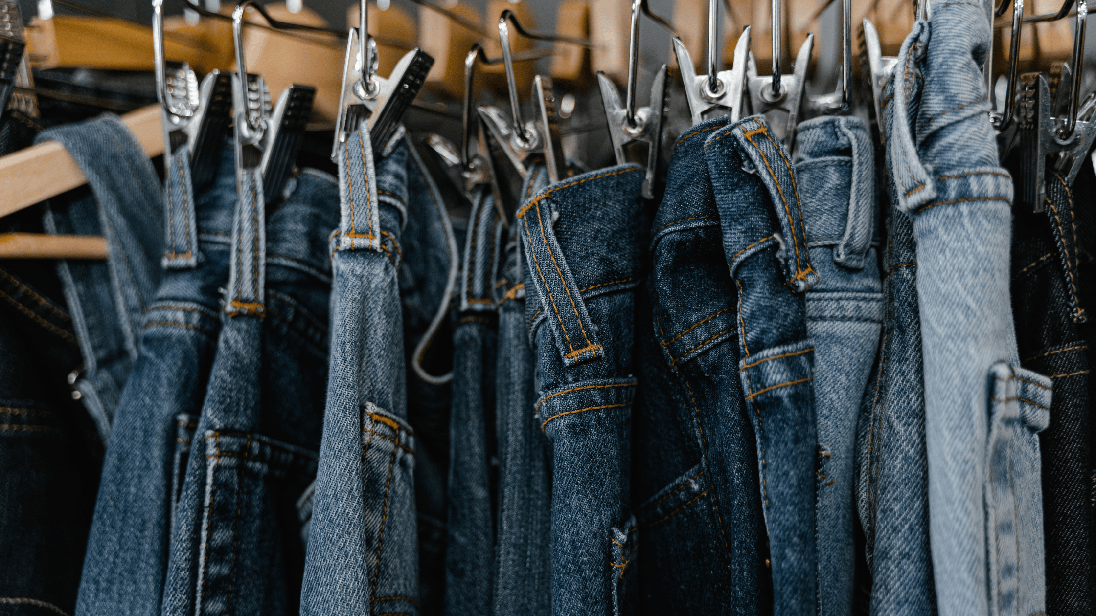 assortment of denim jeans hanging on a rack