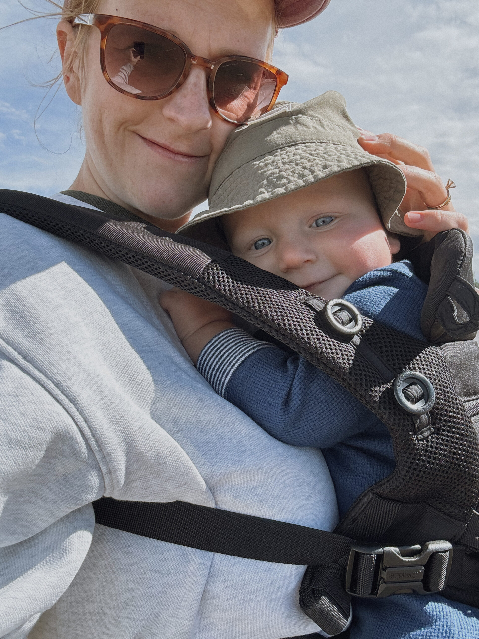 Sisters summer selfie, mom in sunglasses with her baby in a sun hat and carrier