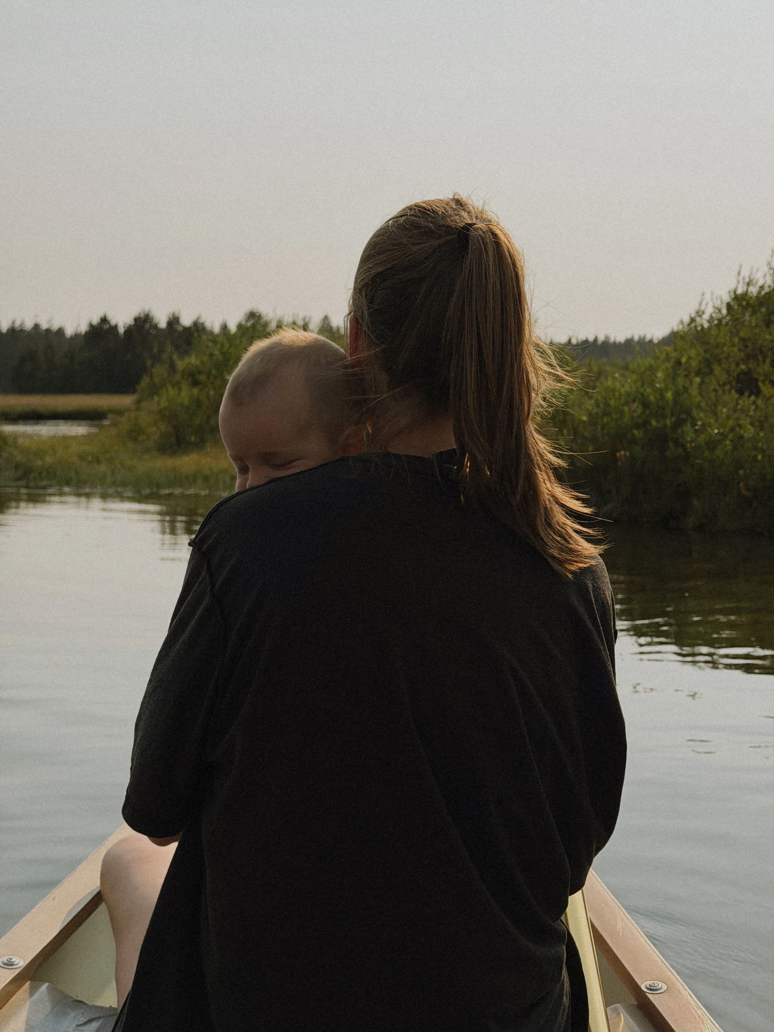 Mom holding her baby in a canoe on a still lake at sunset, one of our summer favorites