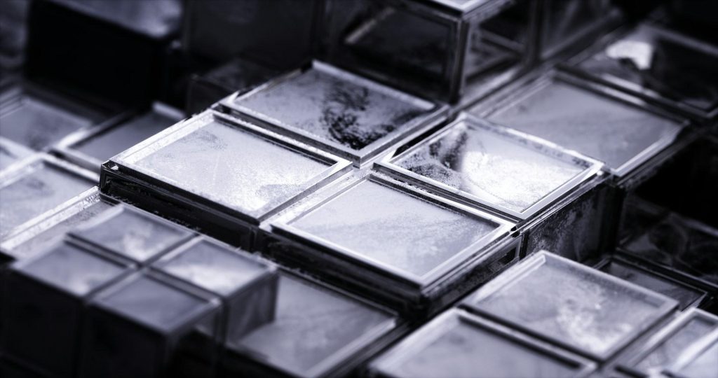 Macro view of an abstract geometric grid of textured silver squares with high-contrast metallic reflections.