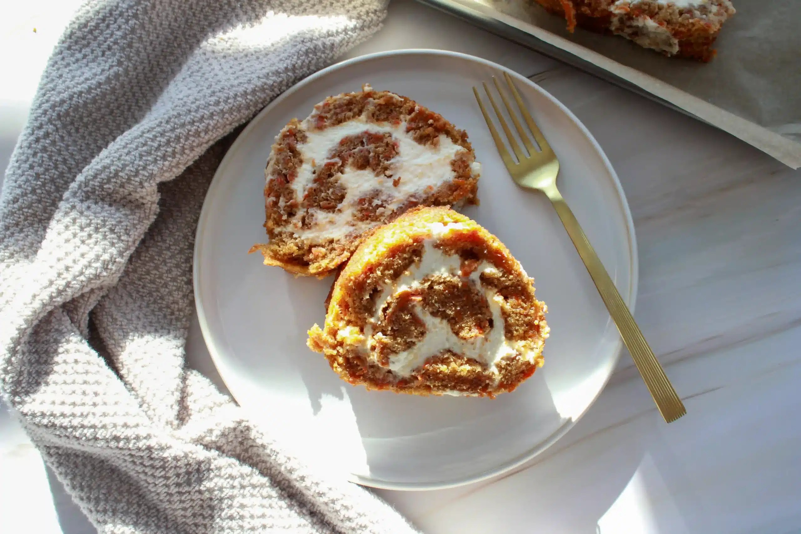 gluten free carrot cake roll with cream cheese frosting on a plate