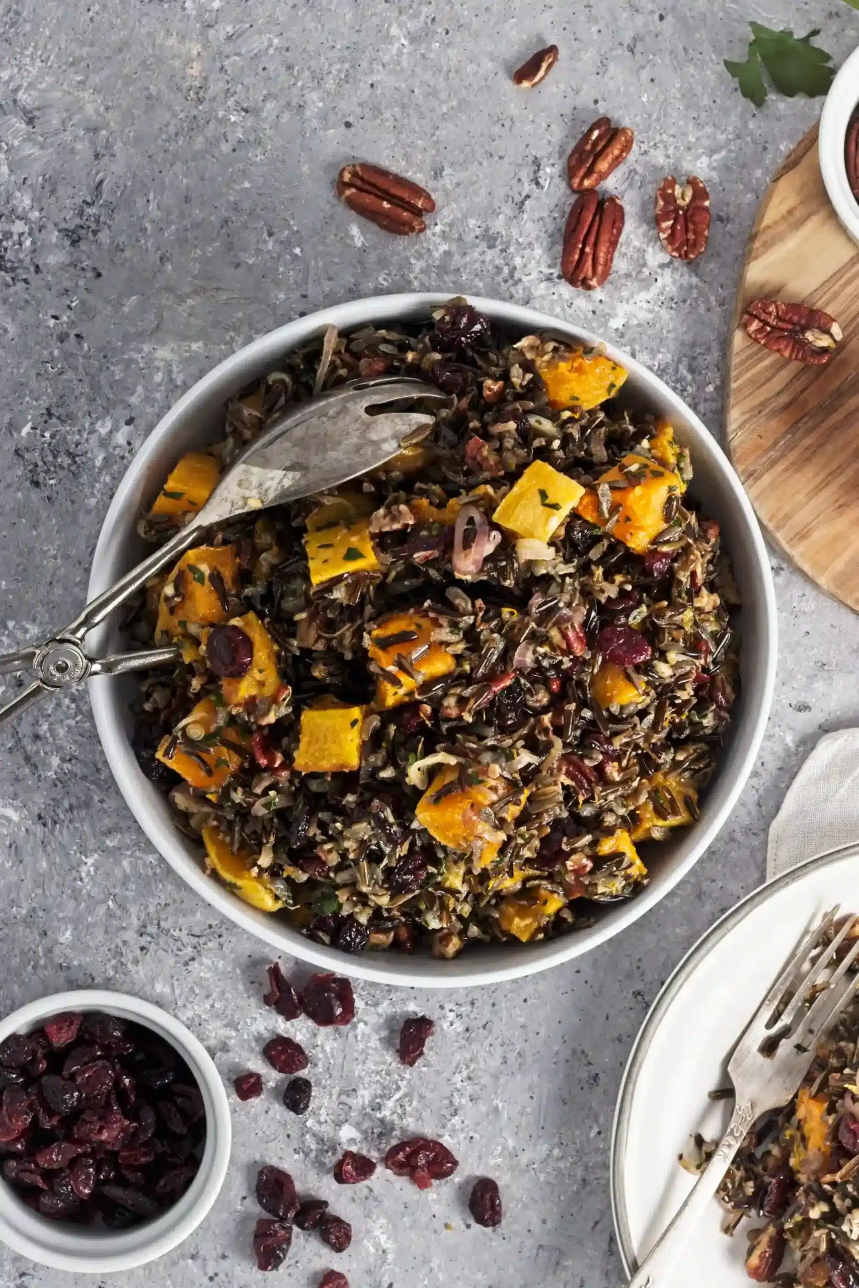 butternut wild rice salad in a large white bowl with a salad fork on a marbled surface