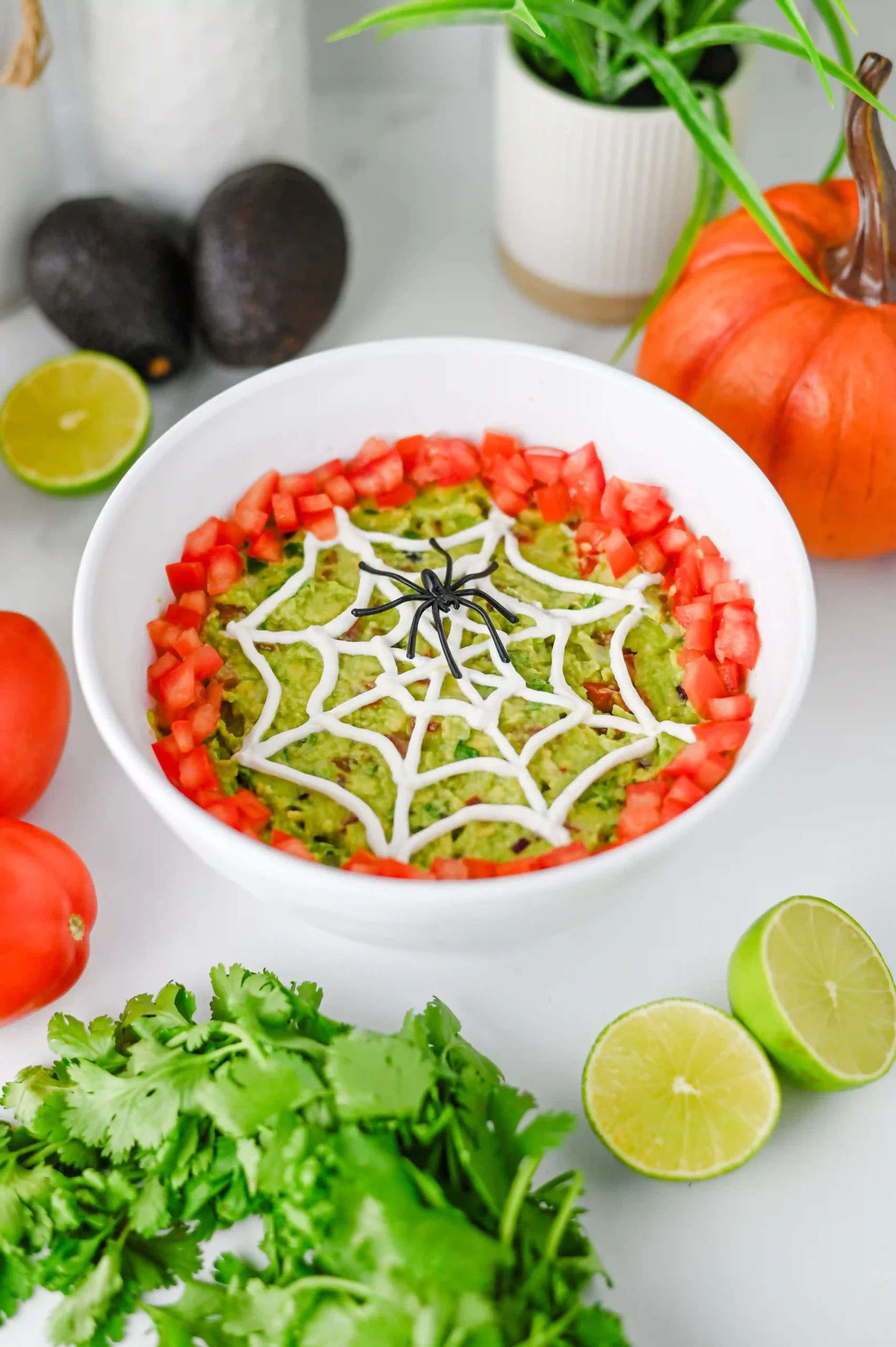 halloween guacamole that uses sour cream to create a web with a plastic spider on it