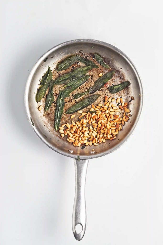pine nuts and sage cooking in a pan